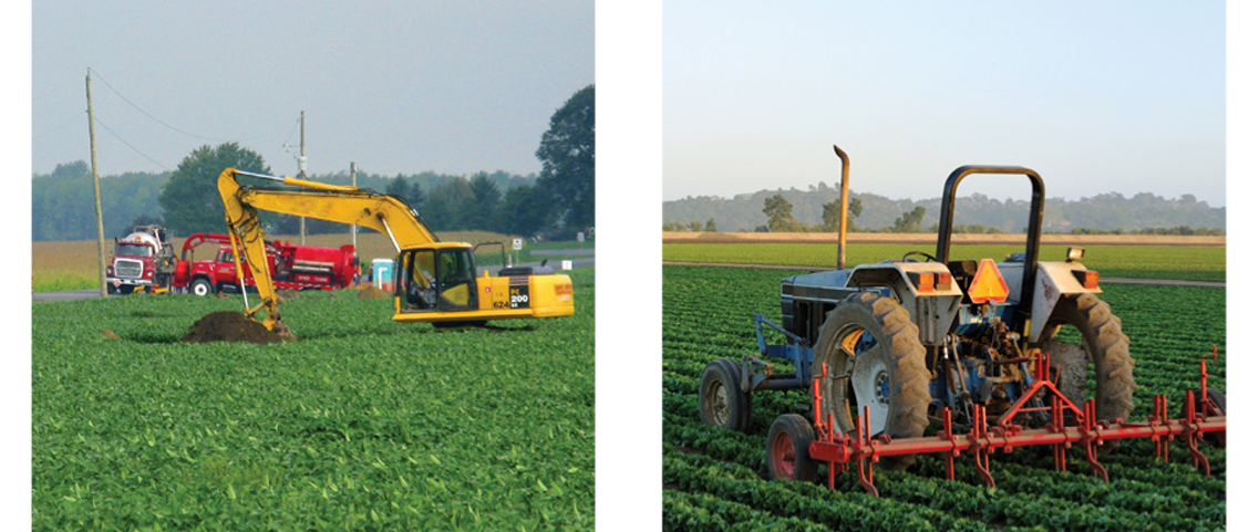 A backhoe is working in a field, with tracks and equipment in the background and an older model tractor sits in a field