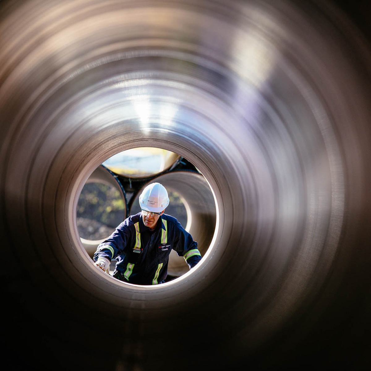 Personne avec port d’équipement de protection personnel qui inspecte l’intérieure d’un pipeline.