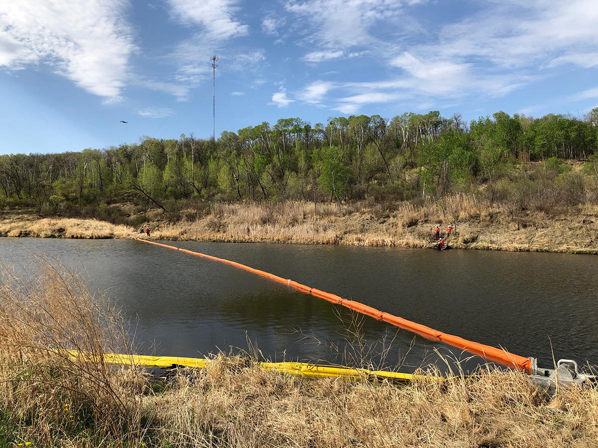 Barrage flottant orange s’étendant sur toute la largeur d’une rivière