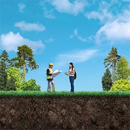 Two people standing in a field surrounded by trees and talking. One is male wearing a safety vest and holding a map. The other is female looking through a binder of notes.
They are in the planning stage of the pipeline lifecycle and are working together to plan a pipeline project.
