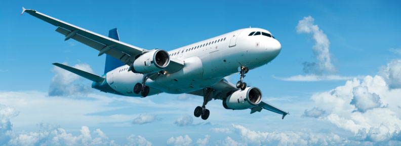 Airplane flies through cloudy blue sky.