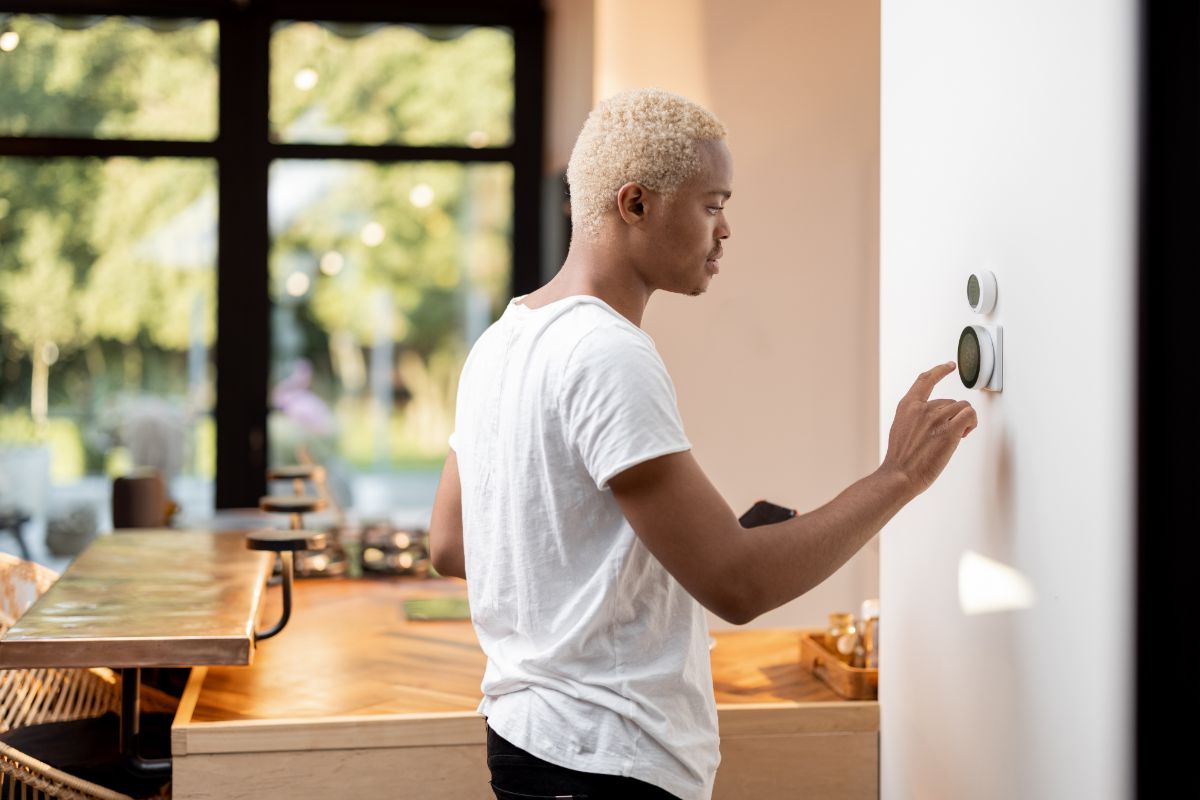Man uses smart energy meter in home while holding smartphone.