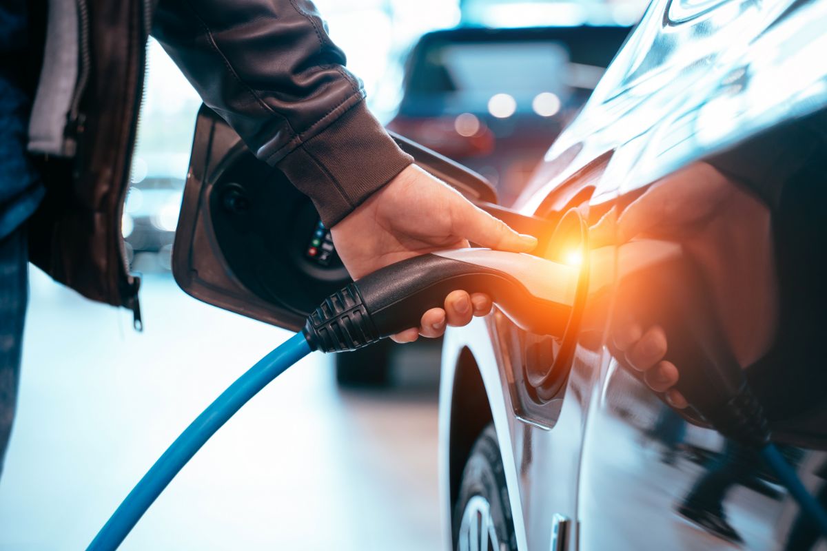 Homme insérant un chargeur dans un véhicule électrique.