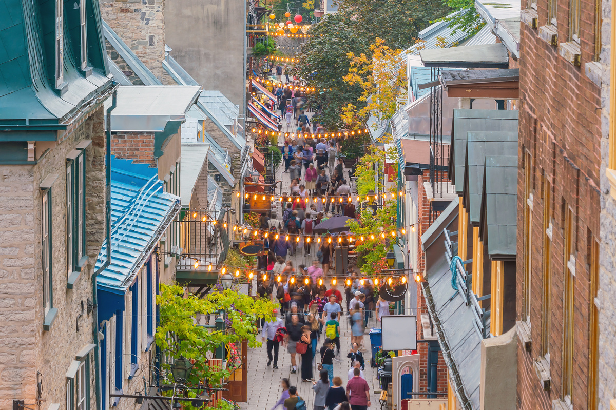 Vue aérienne d'un quartier commerçant animé de Québec, où les lumières du marché brillent au-dessus des têtes des passants.