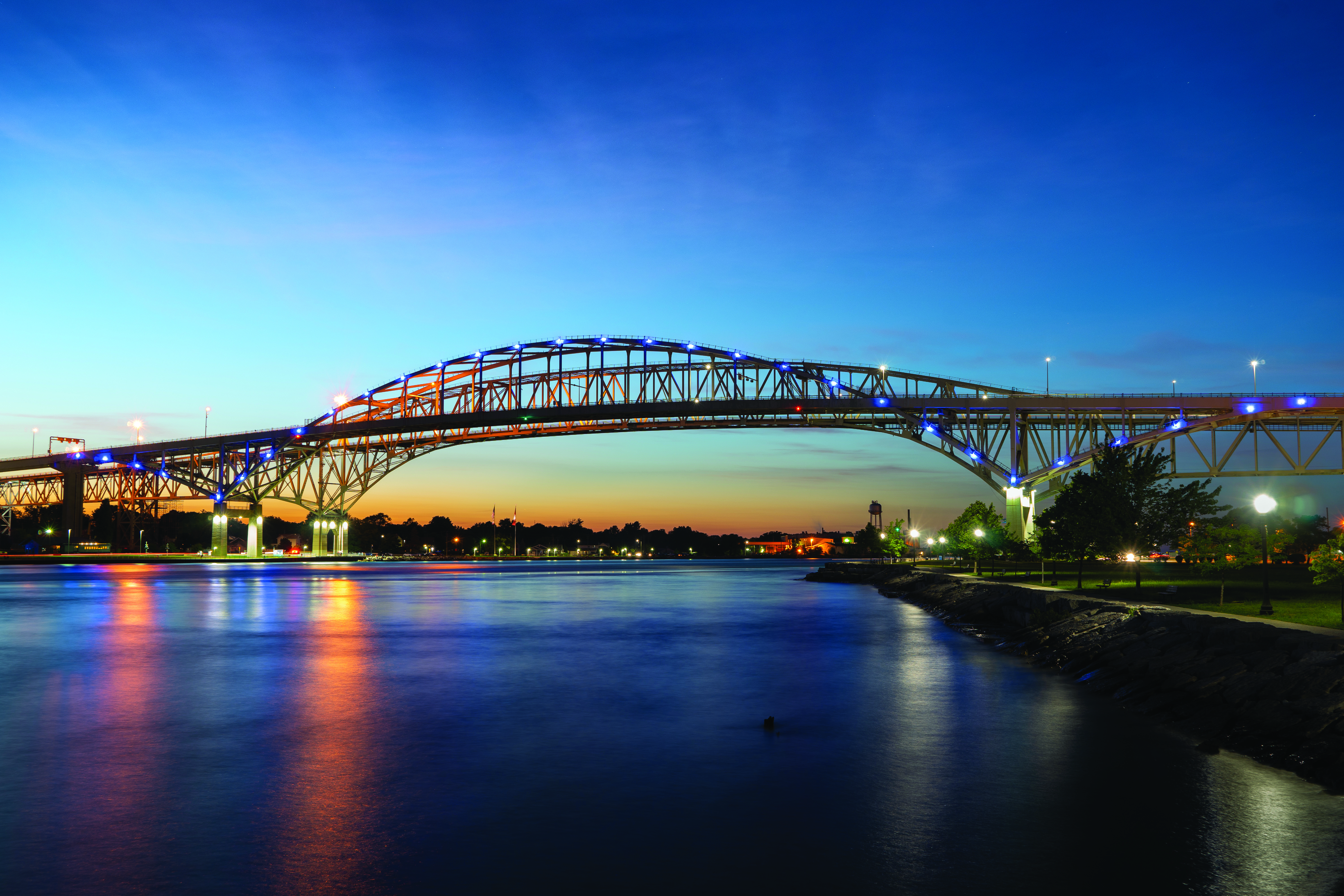 Image of the Blue Water Bridge—an important Canada-U.S. border crossing—at sunset from a perspective of the river below.