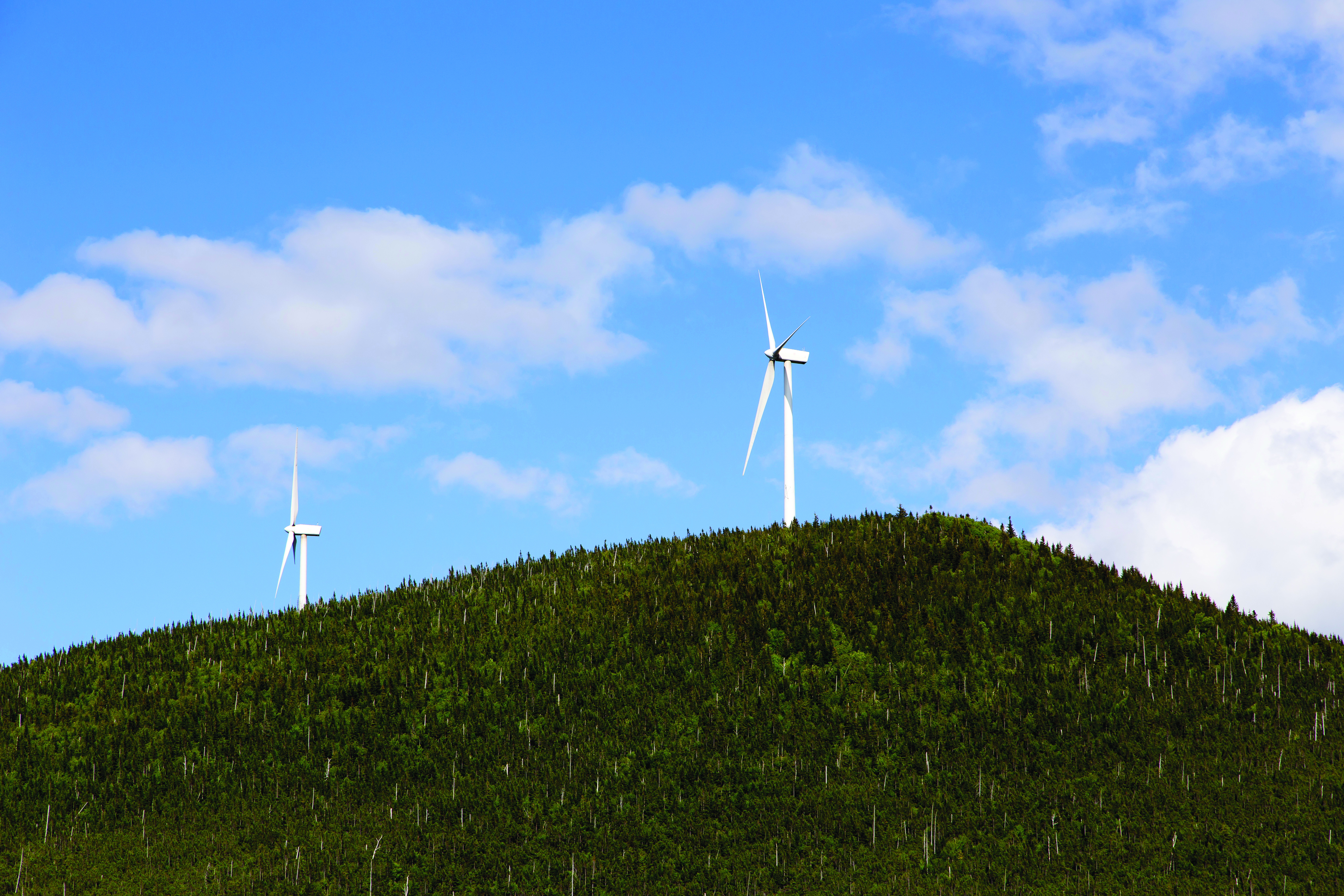 Deux éoliennes sur le Mont Millar, sous un ciel bleu ensoleillé, à Murdochville, au Québec.