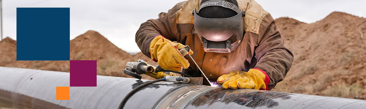Welder on pipe with blue orange and burgandy boxes